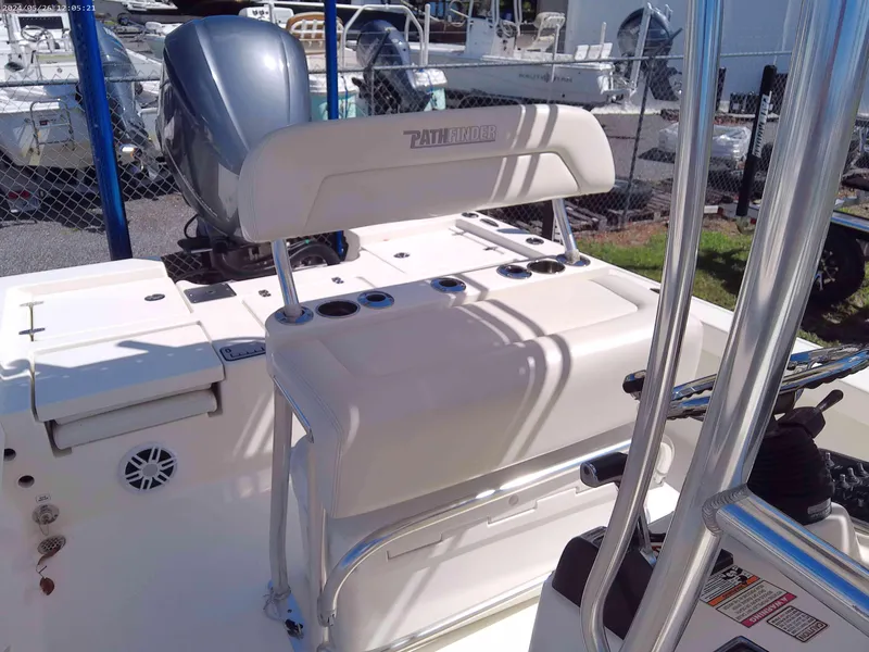 Slide: The Image of 2016 Pathfinder 2400 TRS boat interior with seating and motor, in a marina setting. - 5