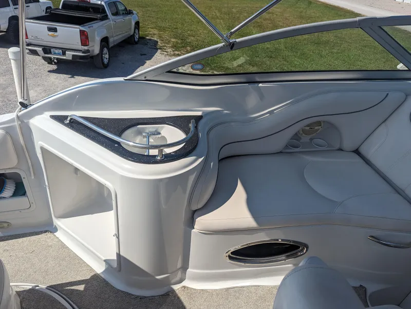 Slide: The Image of 2004 Crownline 250 CR boat interior with seating and storage, parked near a truck. - 16