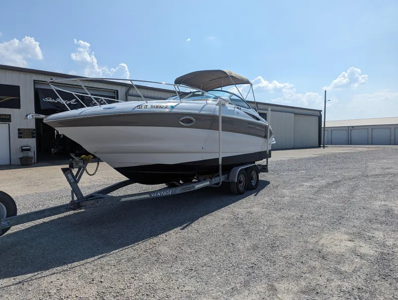 Slide: The Image of 2004 Crownline 250 CR boat on trailer, parked outside storage facility under clear sky. - 2
