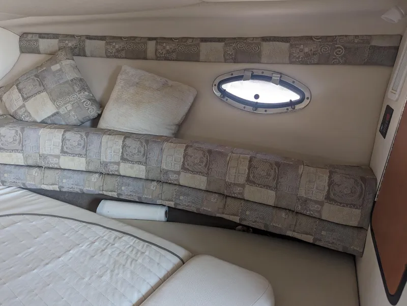 Slide: The Image of 2004 Crownline 250 CR cabin interior with patterned cushions and small porthole window. - 27
