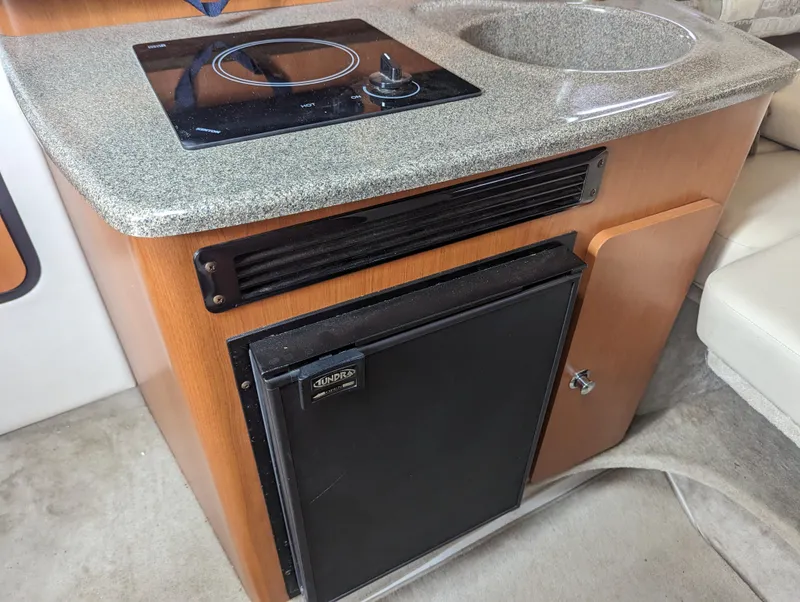 Slide: The Image of 2004 Crownline 250 CR boat kitchenette with stove, sink, and mini fridge. - 30