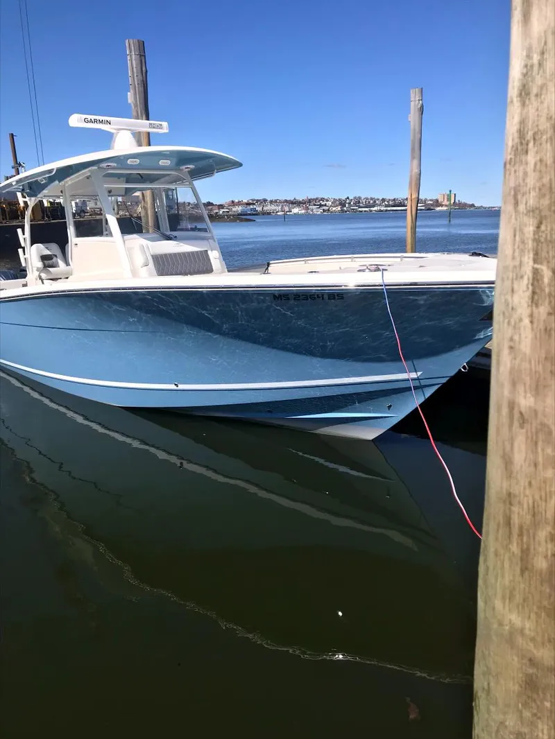 Slide: The Image of 2022 Cobia 350 boat docked on calm water under clear blue sky. - 2
