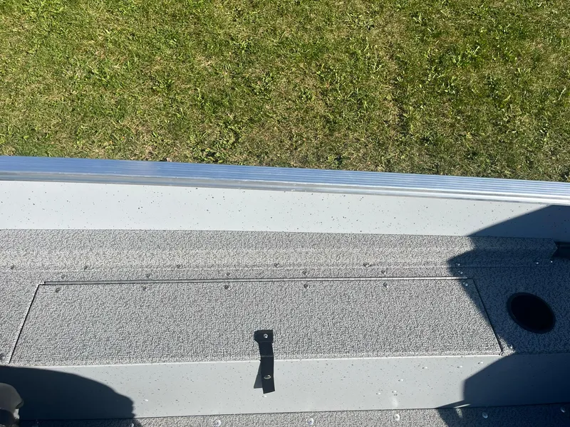 Slide: The Image of 2025 Lund 1600 Fury SS boat interior with storage compartment, grassy background. - 18