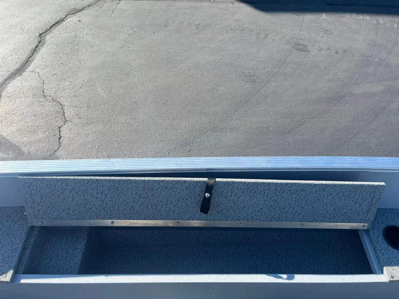 Slide: The Image of 2025 Lund 1600 Fury SS boat storage compartment, open and empty, on a paved surface. - 21