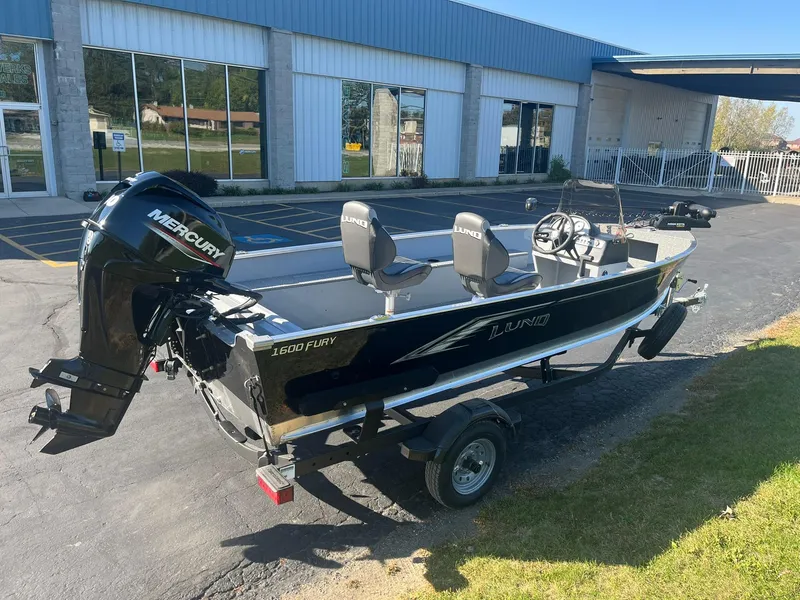 Slide: The Image of 2025 Lund 1600 Fury SS boat with Mercury engine on trailer, parked outside a building. - 5