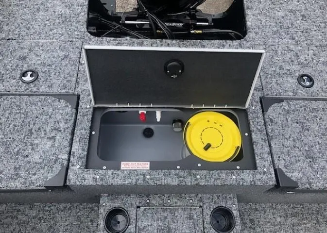 Slide: The Image of 2025 Tracker Targa V18 Combo boat storage compartment with open lid and yellow container. - 26