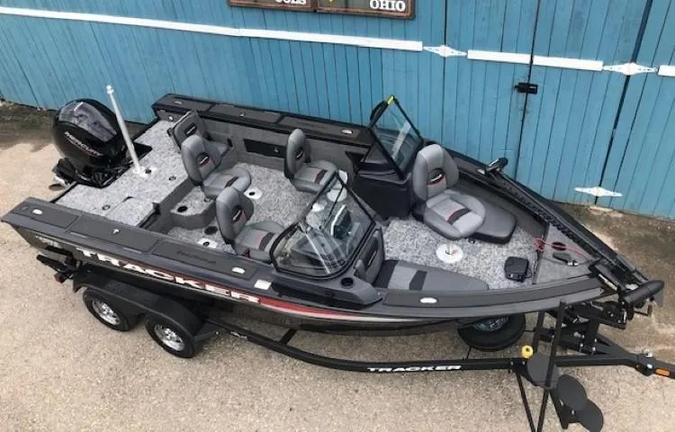 Slide: The Image of 2025 Tracker Targa V18 Combo boat with trailer, parked near a blue wooden wall. - 3