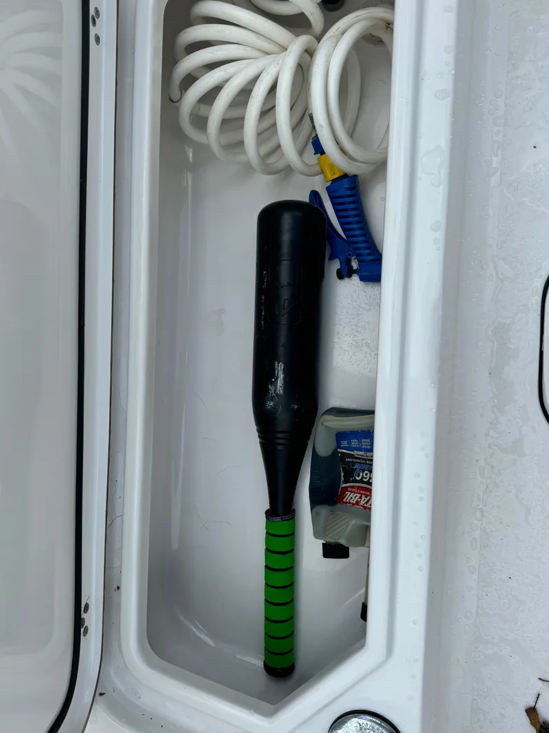 Slide: The Image of Storage compartment in a 2017 Sportsman Masters 267 Bay Boat with coiled hose and black bat. - 38