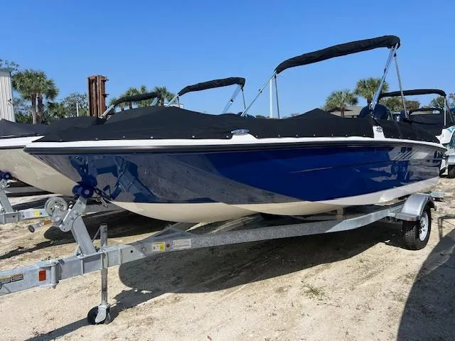 Slide: The Image of 2025 Bayliner Element E18 boat on trailer, blue hull, black cover, sunny day. - 1