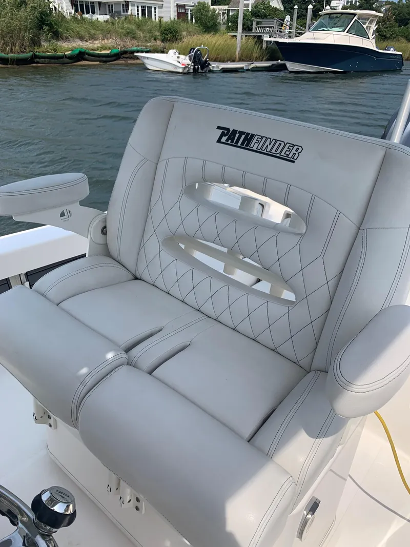 Slide: The Image of 2021 Pathfinder 2600 TRS boat seat with diamond stitching, docked near waterfront homes. - 13