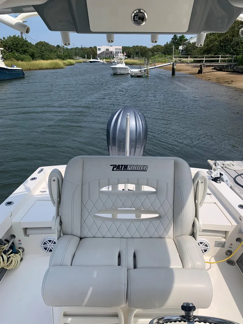 Slide: The Image of 2021 Pathfinder 2600 TRS boat interior with cushioned seating on a calm waterway. - 14