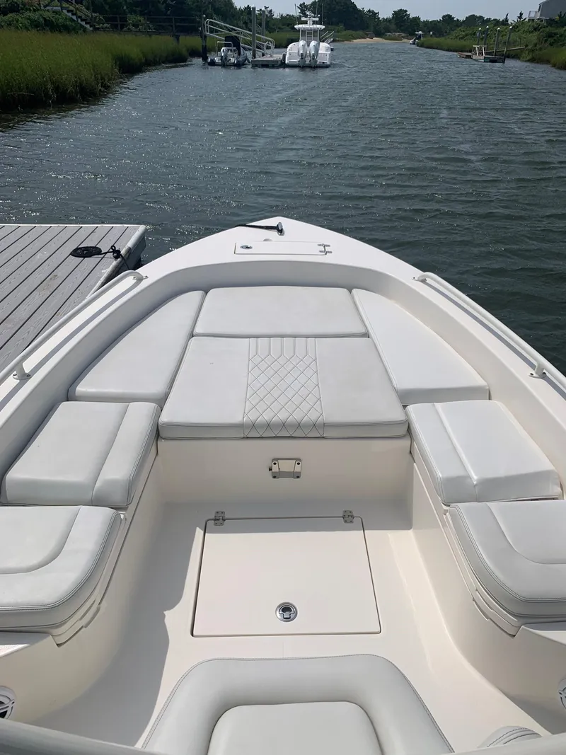 Slide: The Image of 2021 Pathfinder 2600 TRS boat with cushioned seating, docked on a calm waterway. - 15