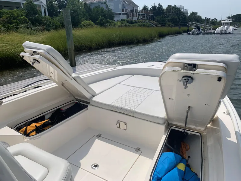 Slide: The Image of 2021 Pathfinder 2600 TRS boat with open storage compartments docked by a grassy shoreline. - 17