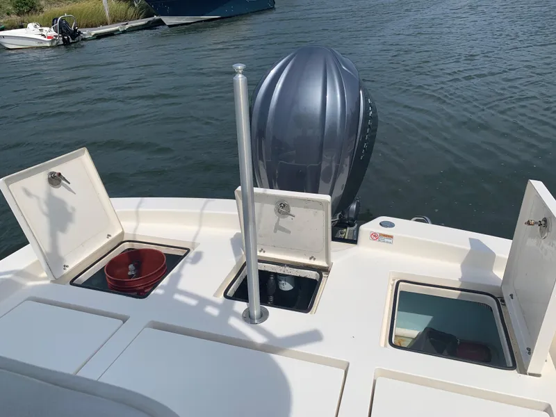 Slide: The Image of 2021 Pathfinder 2600 TRS boat with open storage compartments and outboard motor on water. - 21