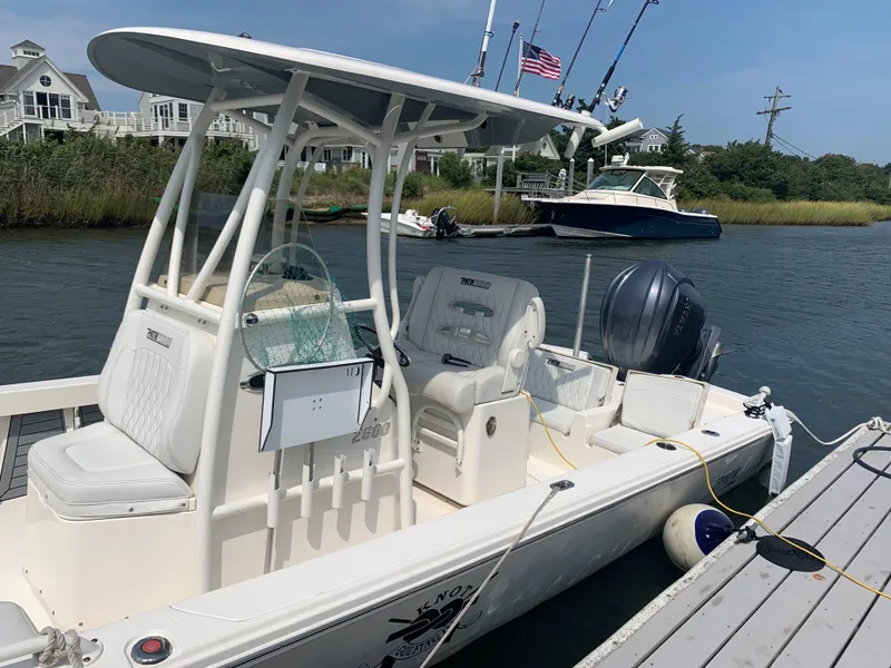 Slide: The Image of 2021 Pathfinder 2600 TRS boat docked near waterfront homes, featuring fishing rods and American flag. - 7