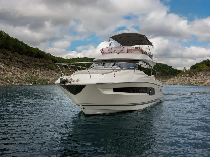 Slide: The Image of 2022 Prestige 460F yacht cruising on a scenic lake under a cloudy sky. - 1