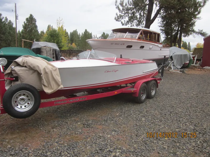 Slide: The Image of 1948 Chris-Craft Racer on red trailer, parked outdoors near trees and other boats. - 12