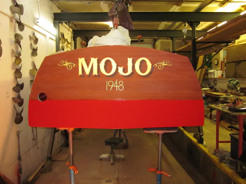 Slide: The Image of 1948 Chris-Craft Racer boat named "MOJO" in workshop, showcasing vintage design. - 16