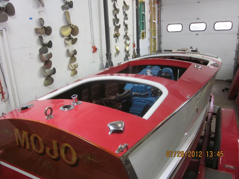 Slide: The Image of 1948 Chris-Craft Racer boat in garage, red and white design, surrounded by propellers. - 18