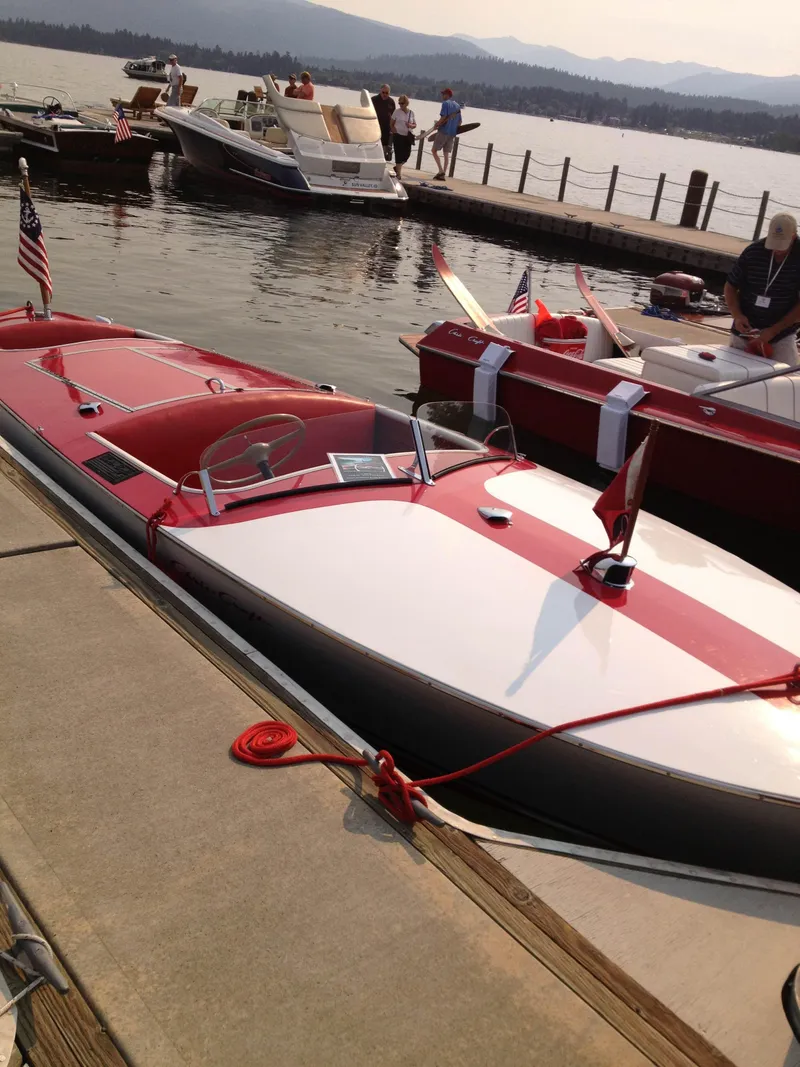 Slide: The Image of 1948 Chris-Craft Racer boat docked, featuring classic red and white design with American flags. - 2