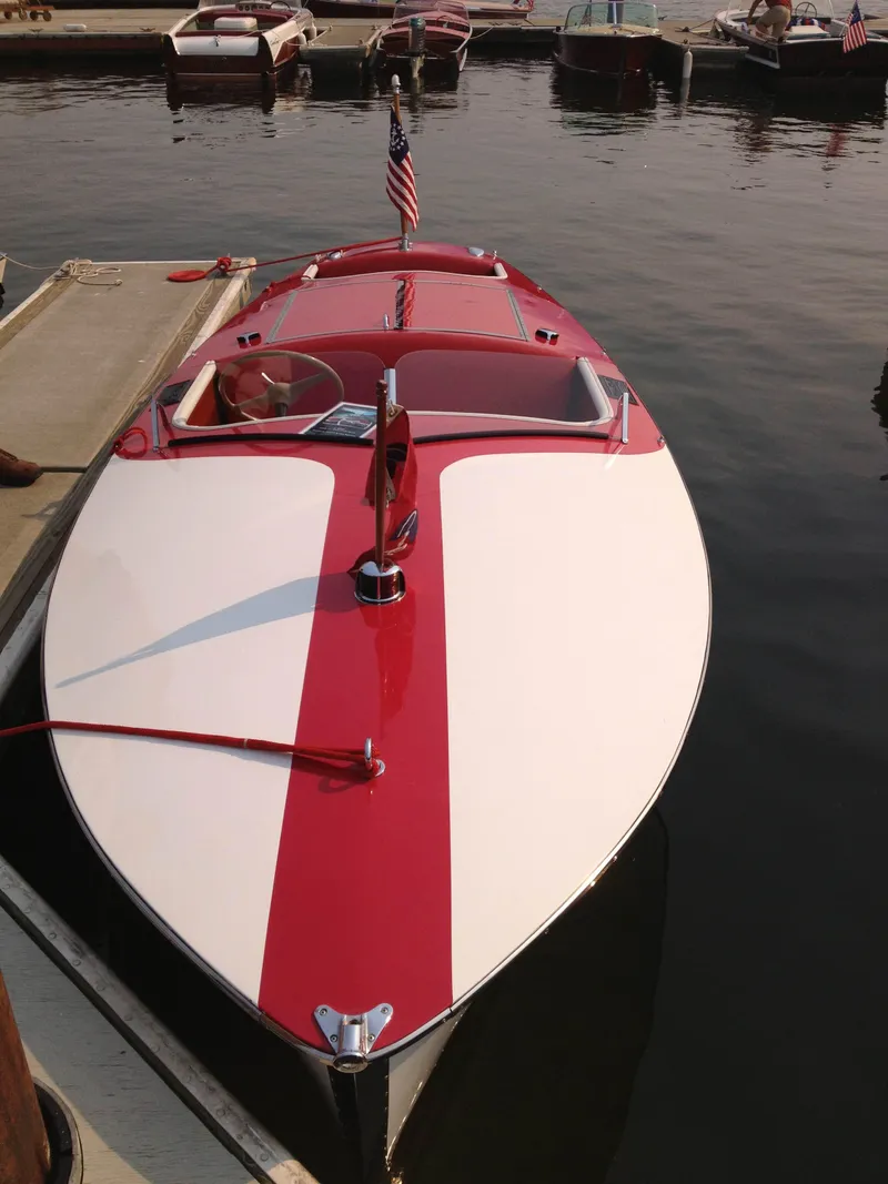 Slide: The Image of 1948 Chris-Craft Racer boat docked, featuring red and white design with American flag. - 3