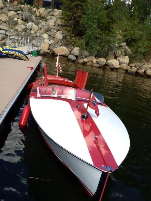 Slide: The Image of 1948 Chris-Craft Racer boat docked by rocky shoreline with trees. - 4