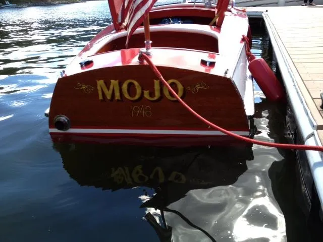 Slide: The Image of 1948 Chris-Craft Racer "Mojo" boat docked, displaying classic wooden design and American flag. - 5