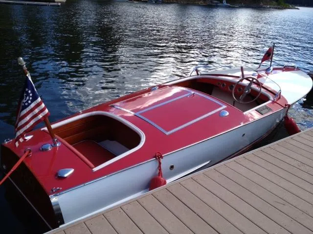 Slide: The Image of 1948 Chris-Craft Racer boat with red and white design docked on a calm lake. - 7