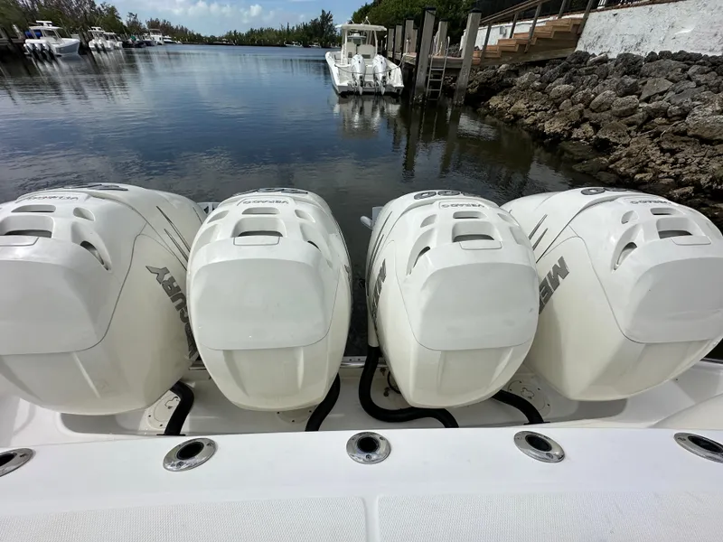 Slide: The Image of Boston Whaler 420 Outrage 2020 with four Mercury outboard engines docked by a serene waterway. - 15
