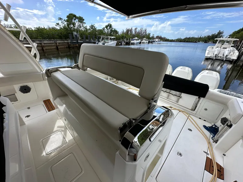 Slide: The Image of 2020 Boston Whaler 420 Outrage boat interior with seating, docked by a scenic waterway. - 19