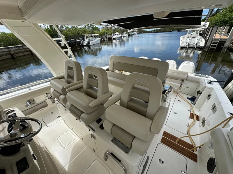 Slide: The Image of 2020 Boston Whaler 420 Outrage boat interior with luxurious seating and helm, docked by a serene waterway. - 23
