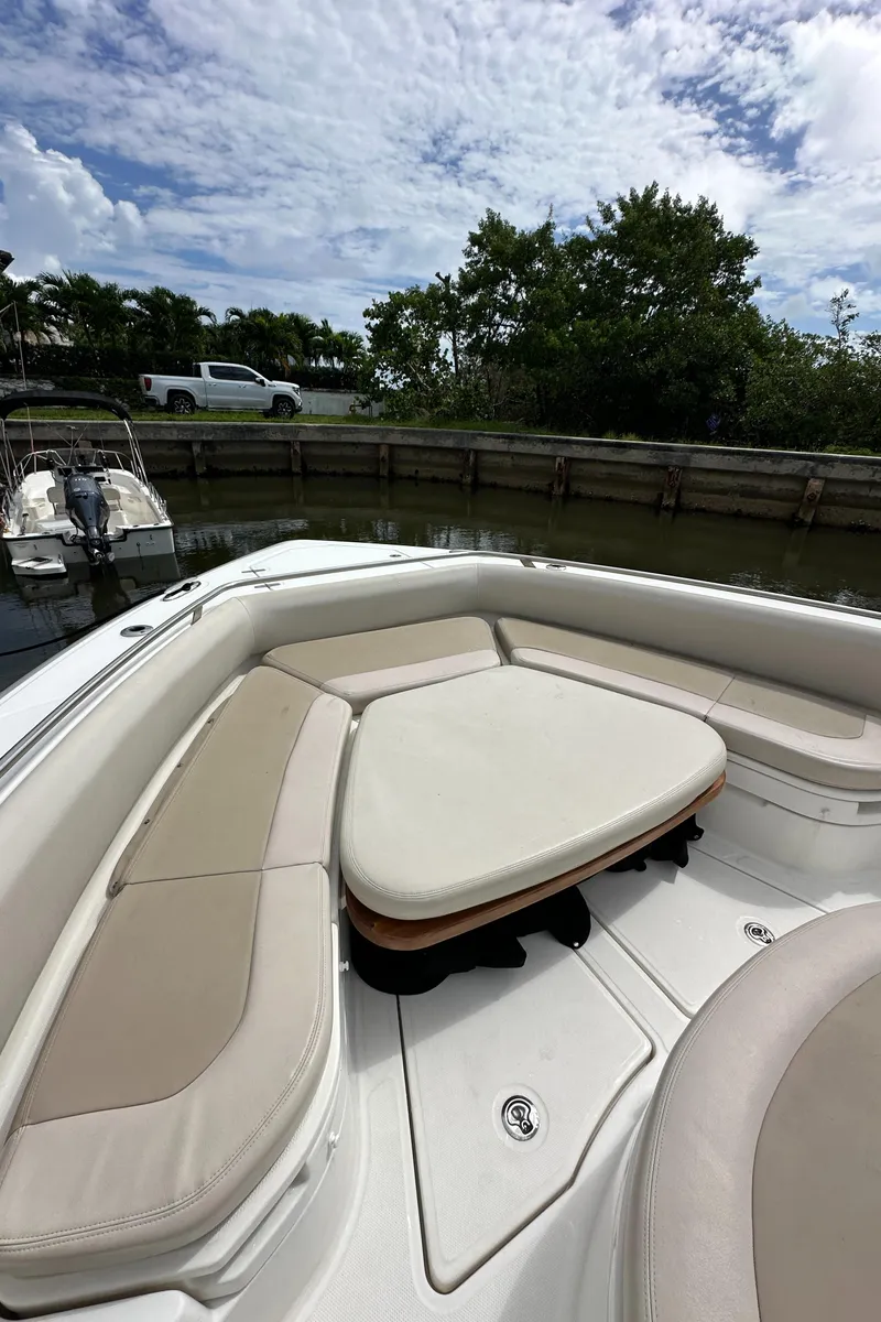 Slide: The Image of 2020 Boston Whaler 420 Outrage boat interior with cushioned seating under a cloudy sky. - 40