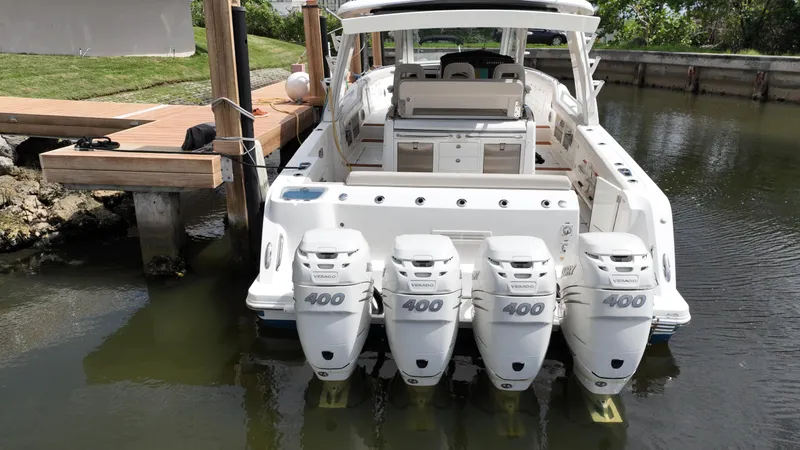 Slide: The Image of 2020 Boston Whaler 420 Outrage with four powerful outboard engines docked in calm water. - 9