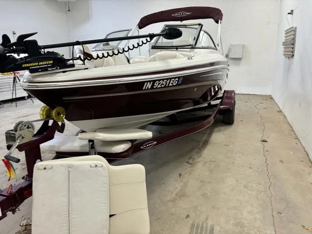 Slide: The Image of 2013 Tahoe Q5i SF boat in garage, maroon and white, with trailer and trolling motor. - 23
