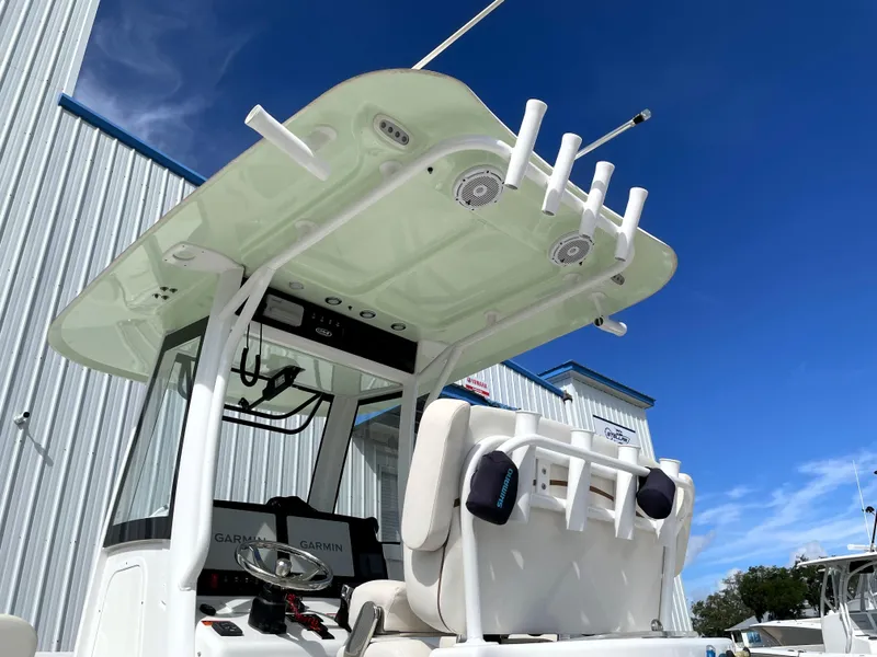 Slide: The Image of 2022 Sea Hunt Gamefish 25 boat with T-top and rod holders against blue sky. - 17