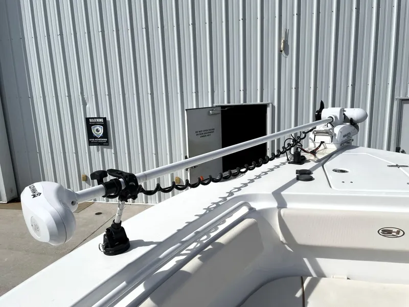 Slide: The Image of 2022 Sea Hunt Gamefish 25 boat with mounted trolling motor, docked near a corrugated metal building. - 24