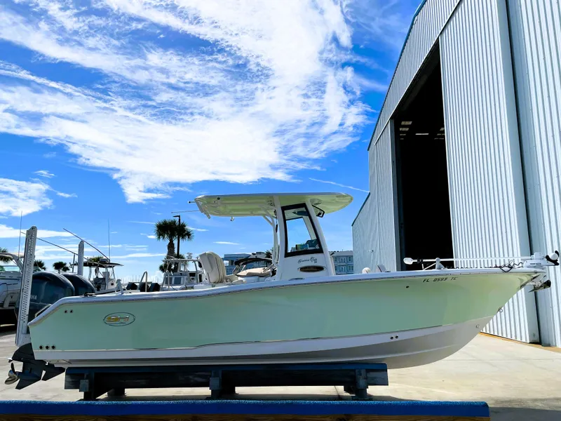 Slide: The Image of 2022 Sea Hunt Gamefish 25 boat near a large storage facility under a blue sky. - 4