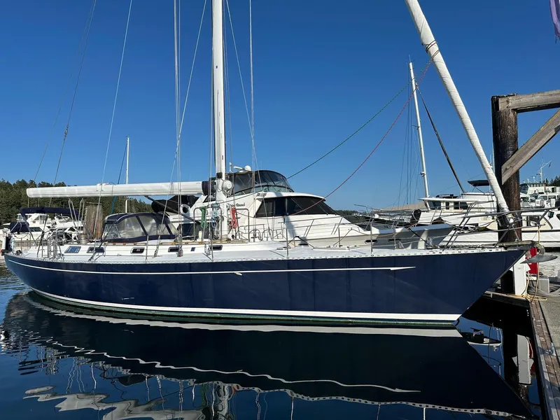 Slide: The Image of 1986 Cheoy Lee Pedrick 55 Sloop docked in a marina under clear blue skies. - 0