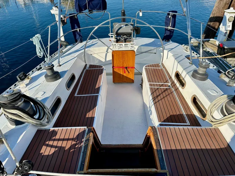 Slide: The Image of 1986 Cheoy Lee Pedrick 55 Sloop cockpit with wooden seating and steering wheel, docked at marina. - 11