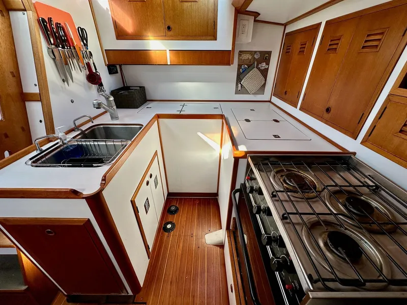 Slide: The Image of 1986 Cheoy Lee Pedrick 55 Sloop galley with stove, sink, and wooden cabinetry. - 3