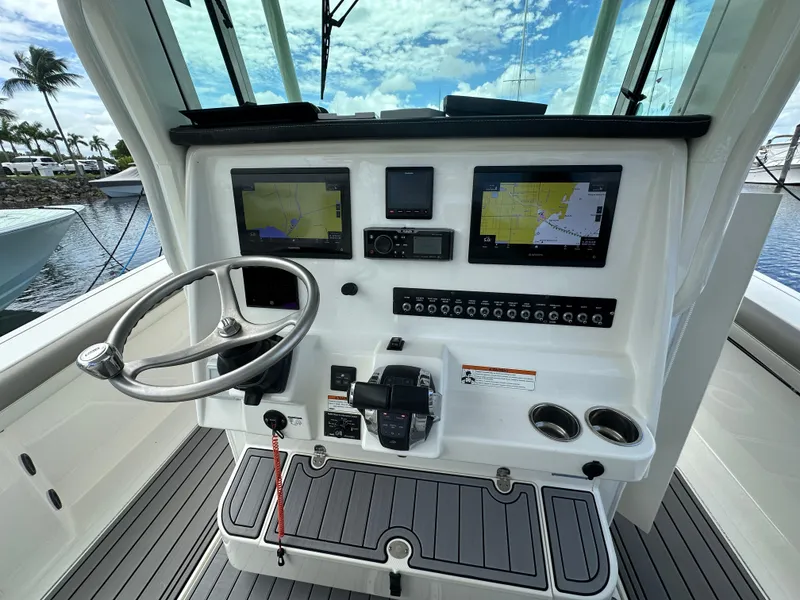 Slide: The Image of 2020 World Cat 325 CC boat dashboard with dual navigation screens and steering wheel. - 5