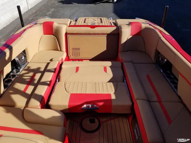 Slide: The Image of 2021 MasterCraft X26 boat interior with tan and red upholstery, featuring spacious seating and cup holders. - 14