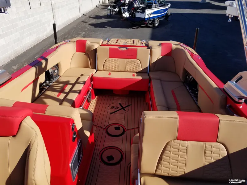 Slide: The Image of 2021 MasterCraft X26 boat interior with red and beige seating, docked outdoors. - 15