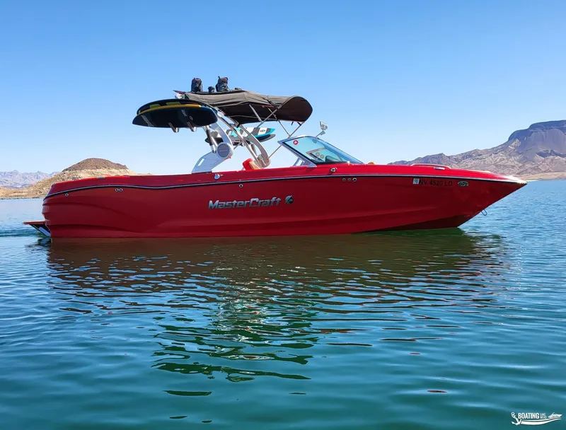 Slide: The Image of 2021 MasterCraft X26 boat in vibrant red on a serene lake. - 2