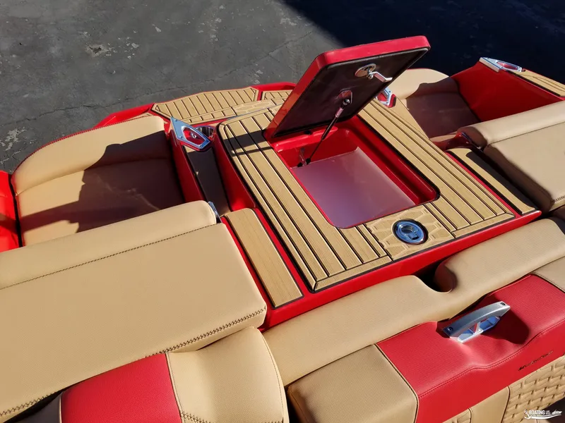 Slide: The Image of 2021 MasterCraft X26 boat interior with tan and red upholstery, featuring a storage compartment. - 28
