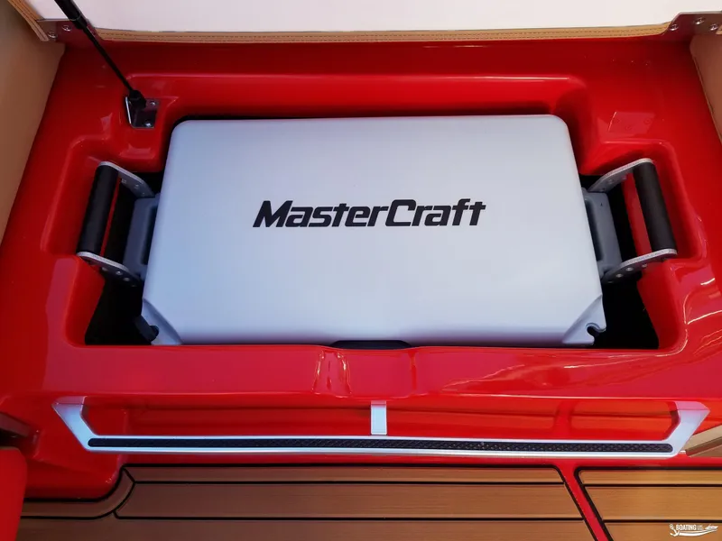 Slide: The Image of MasterCraft X26 2021 boat storage compartment with branded cooler, red interior. - 29