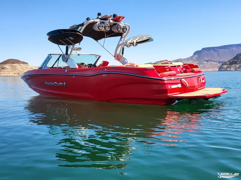 Slide: The Image of Red 2021 MasterCraft X26 boat on a serene lake with mountainous backdrop. - 3