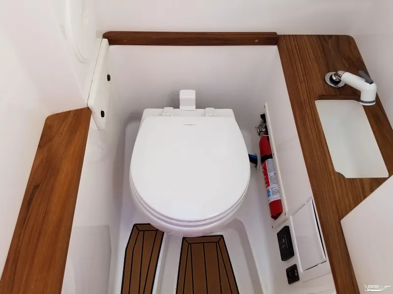 Slide: The Image of 2021 MasterCraft X26 boat bathroom with toilet, sink, and fire extinguisher. - 32