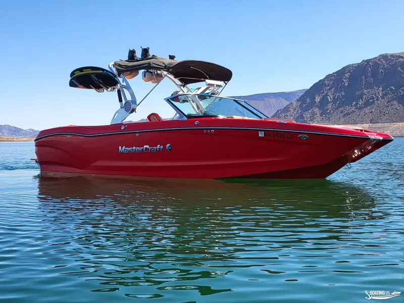 Slide: The Image of 2021 MasterCraft X26 boat on a serene lake with mountainous backdrop. - 5