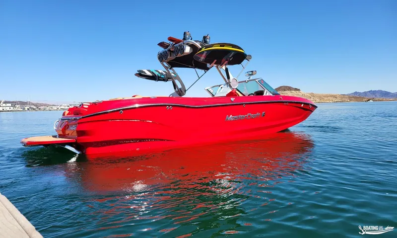 Slide: The Image of Red 2021 MasterCraft X26 boat on a lake, clear blue sky background. - 6